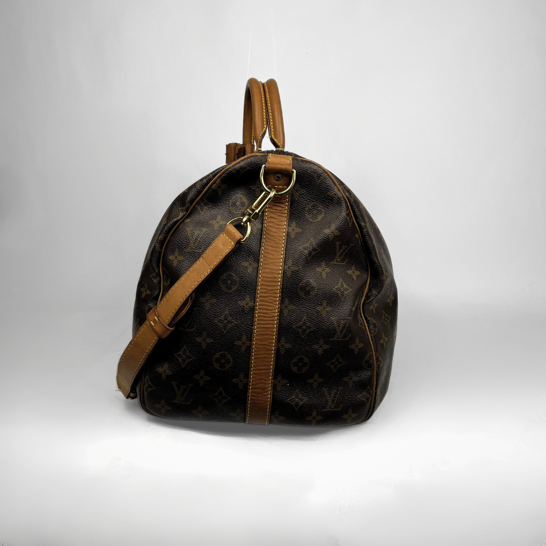 Louis Vuitton monogram canvas Keepall bag with tan leather handles and strap, shown from the side against a light gray studio background.