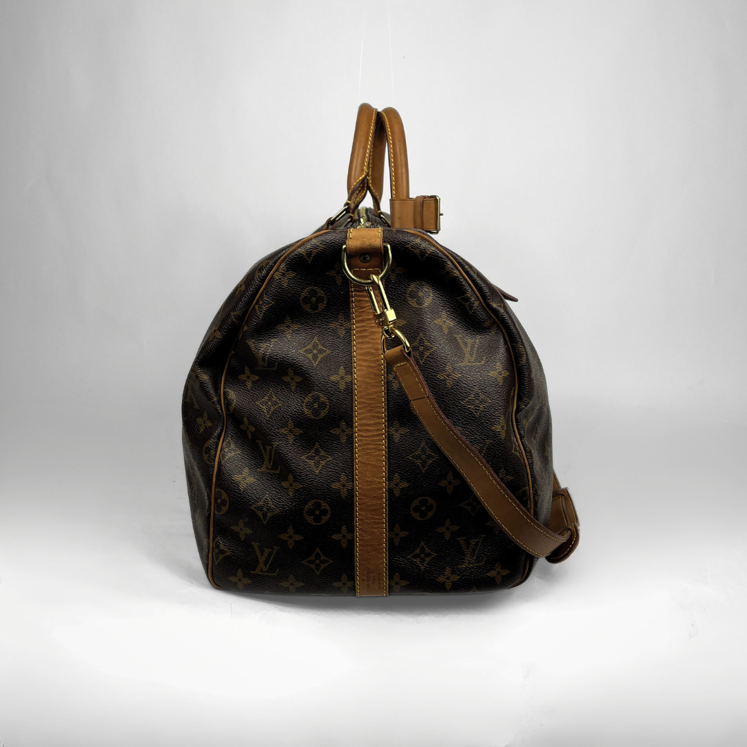 A Louis Vuitton monogram Keepall bag in dark brown coated canvas with tan leather trim, handles, and strap, shown against a plain light gray background.