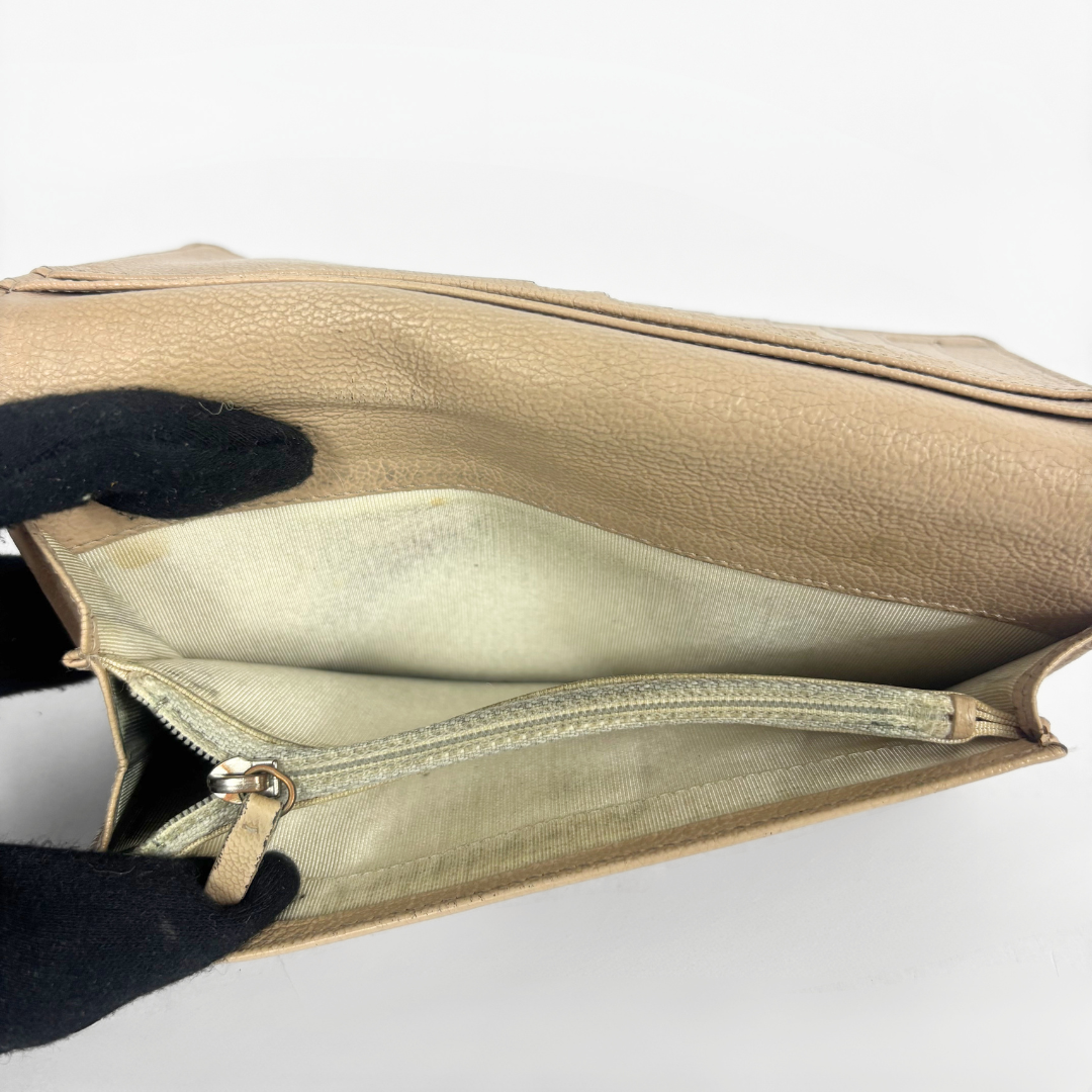 Inside of the wallet (beige) with a gold zipper on a white background