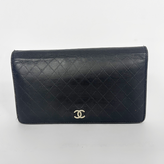 Black quilted wallet with Chanel logo on a white background