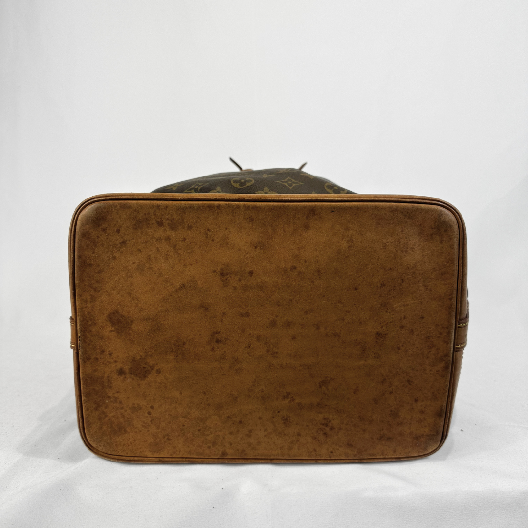 A vintage Louis Vuitton brown leather suitcase or duffel bag shown from the back, featuring the classic monogram pattern and a heavily worn, distressed brown leather exterior.