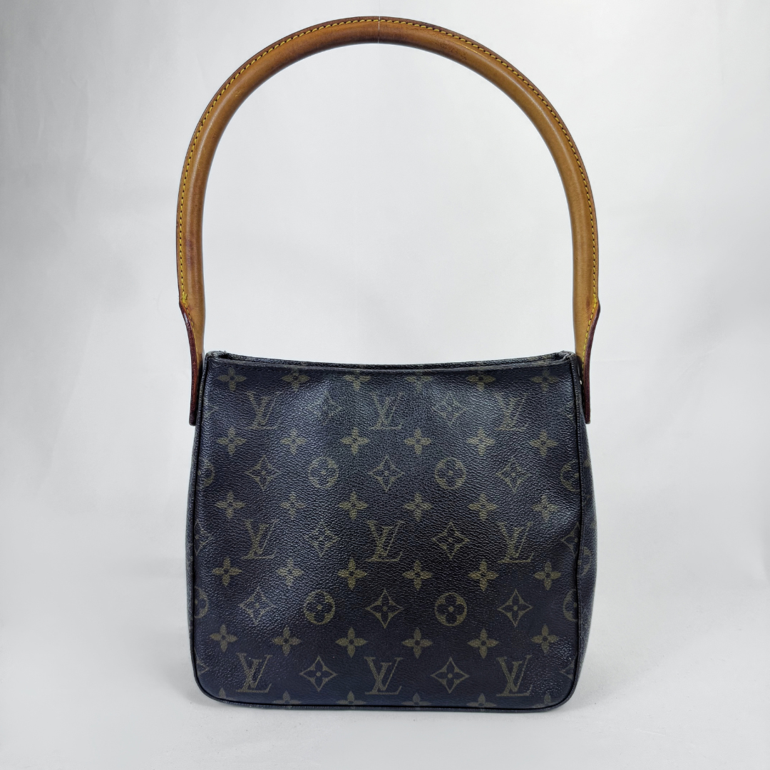 A Louis Vuitton shoulder bag in dark navy monogram canvas with a tan leather top handle, photographed against a light gray studio background.