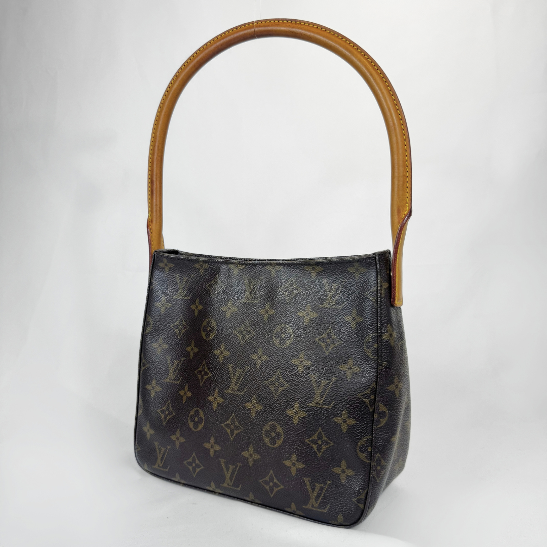 A Louis Vuitton shoulder bag in dark brown monogram canvas with tan leather trim and a matching top handle, photographed against a plain light gray background.