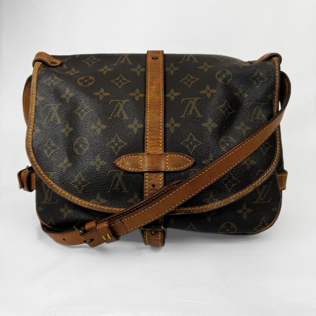 Louis Vuitton monogram canvas shoulder bag with tan leather trim and strap, photographed against a plain white background.