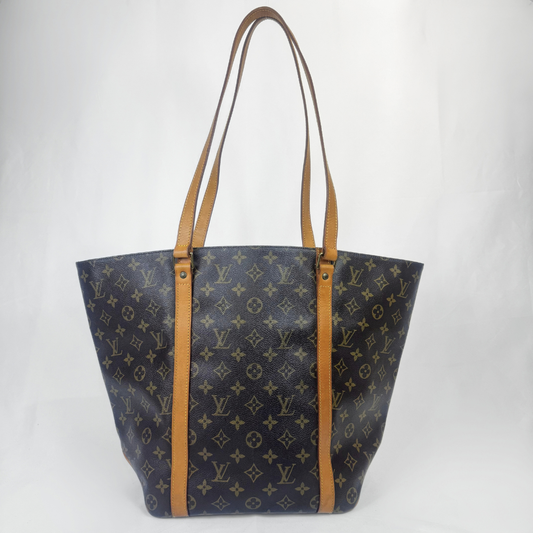 Louis Vuitton monogram canvas tote bag with tan leather shoulder straps and trim, photographed against a white studio background.