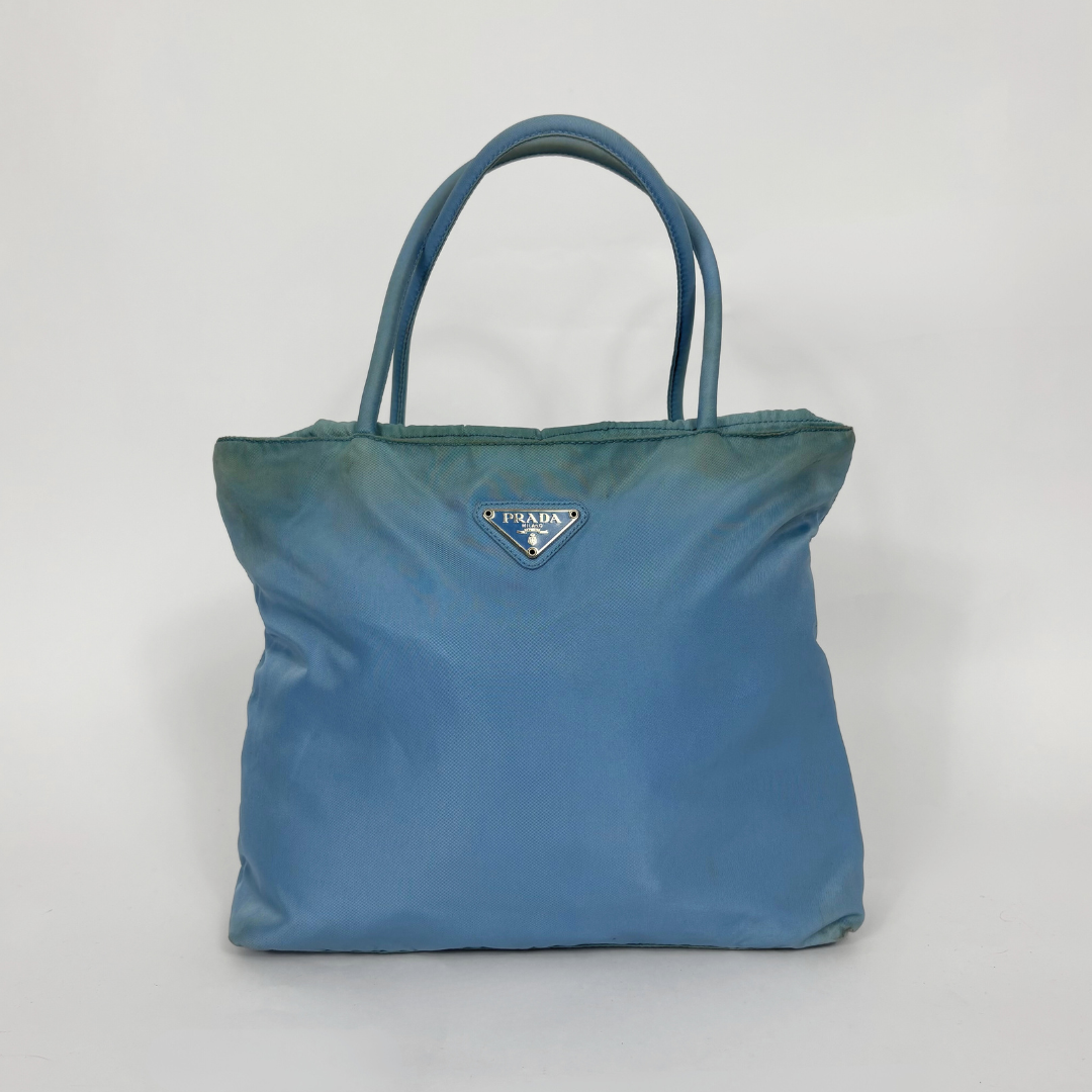 Prada light blue nylon tote bag with matching top handles and the signature enamel triangle logo.