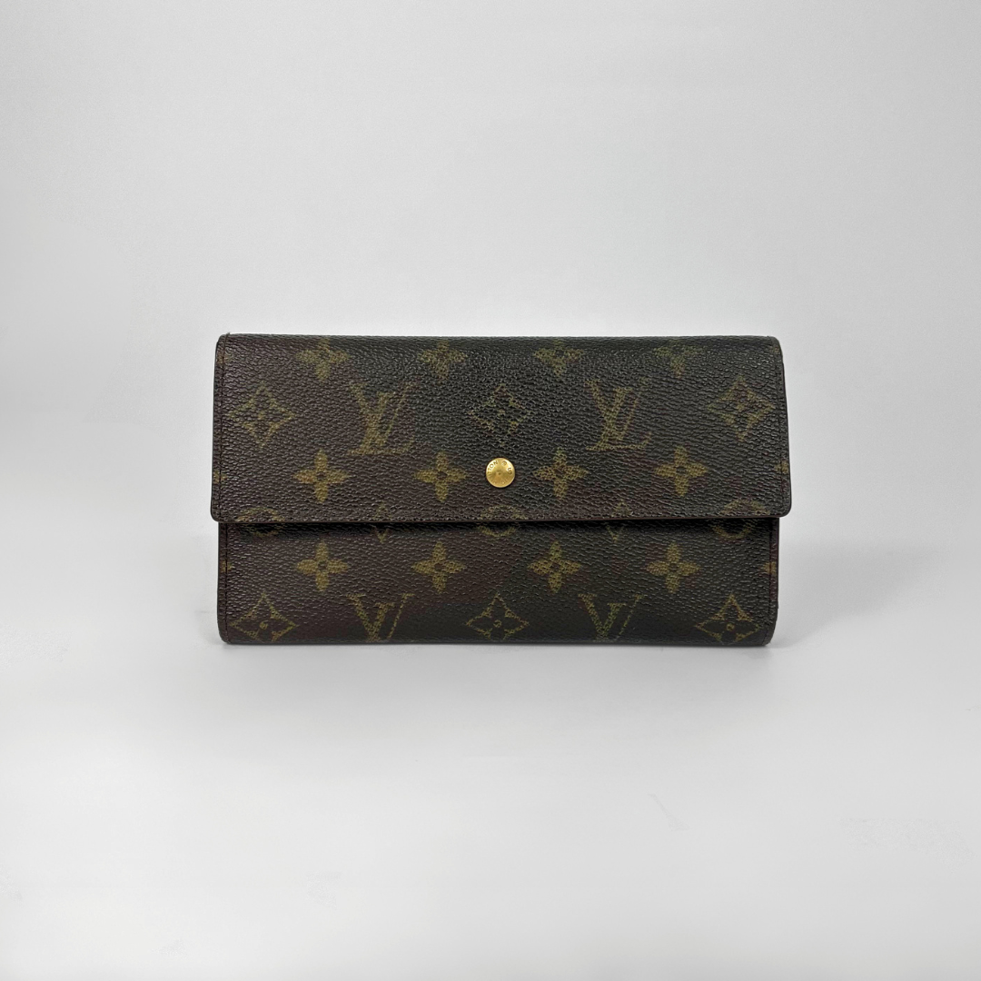 Brown wallet with gold monogram pattern on a light gray background