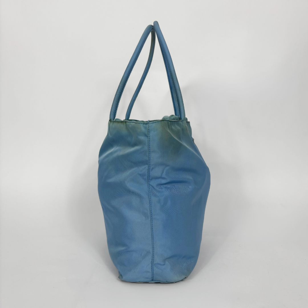 Prada light blue nylon tote bag with matching top handles and the signature enamel triangle logo.