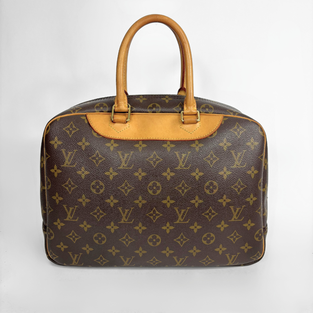 A Louis Vuitton monogram canvas duffel bag with tan leather handles and trim, photographed against a light gray background.