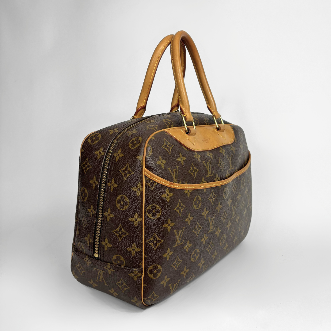 A Louis Vuitton monogram canvas duffel bag with tan leather handles and trim, photographed on a light gray studio background.