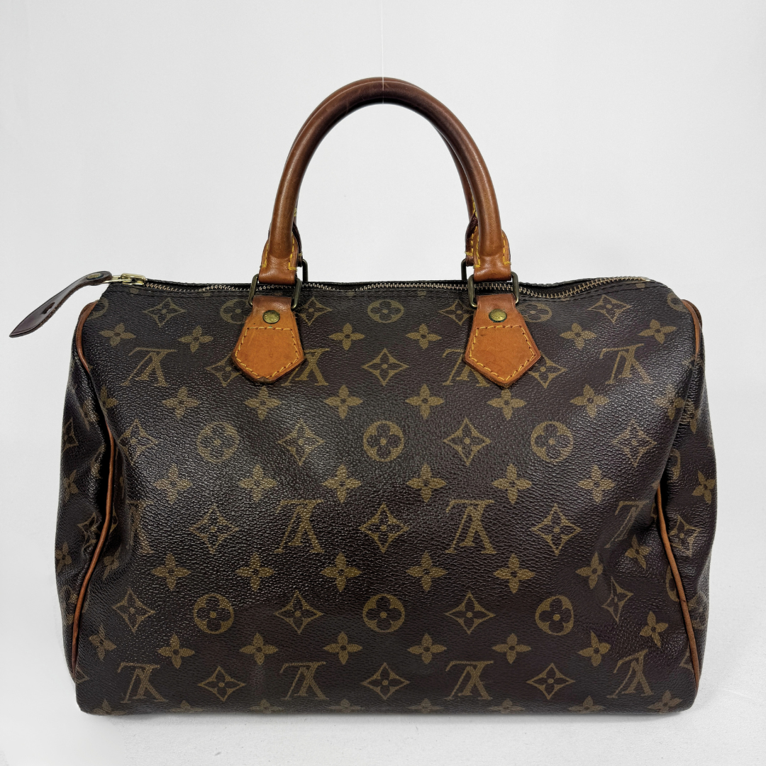 A Louis Vuitton monogram canvas Speedy handbag in dark brown with tan leather handles and trim, photographed against a plain white background.