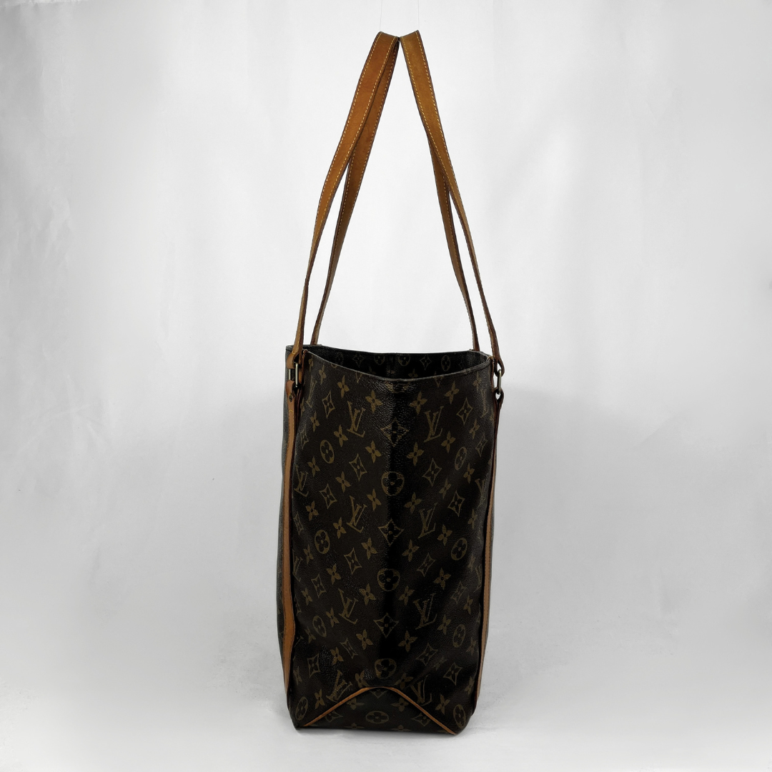 A Louis Vuitton monogram tote bag in dark brown coated canvas with tan leather shoulder straps, shown against a plain light gray background.