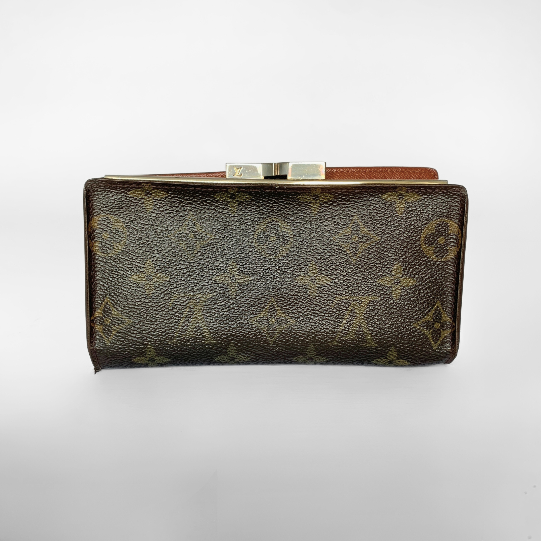 A Louis Vuitton monogram canvas clutch wallet with a brown leather strap and a silver-tone metal clasp, shown against a plain light gray background.
