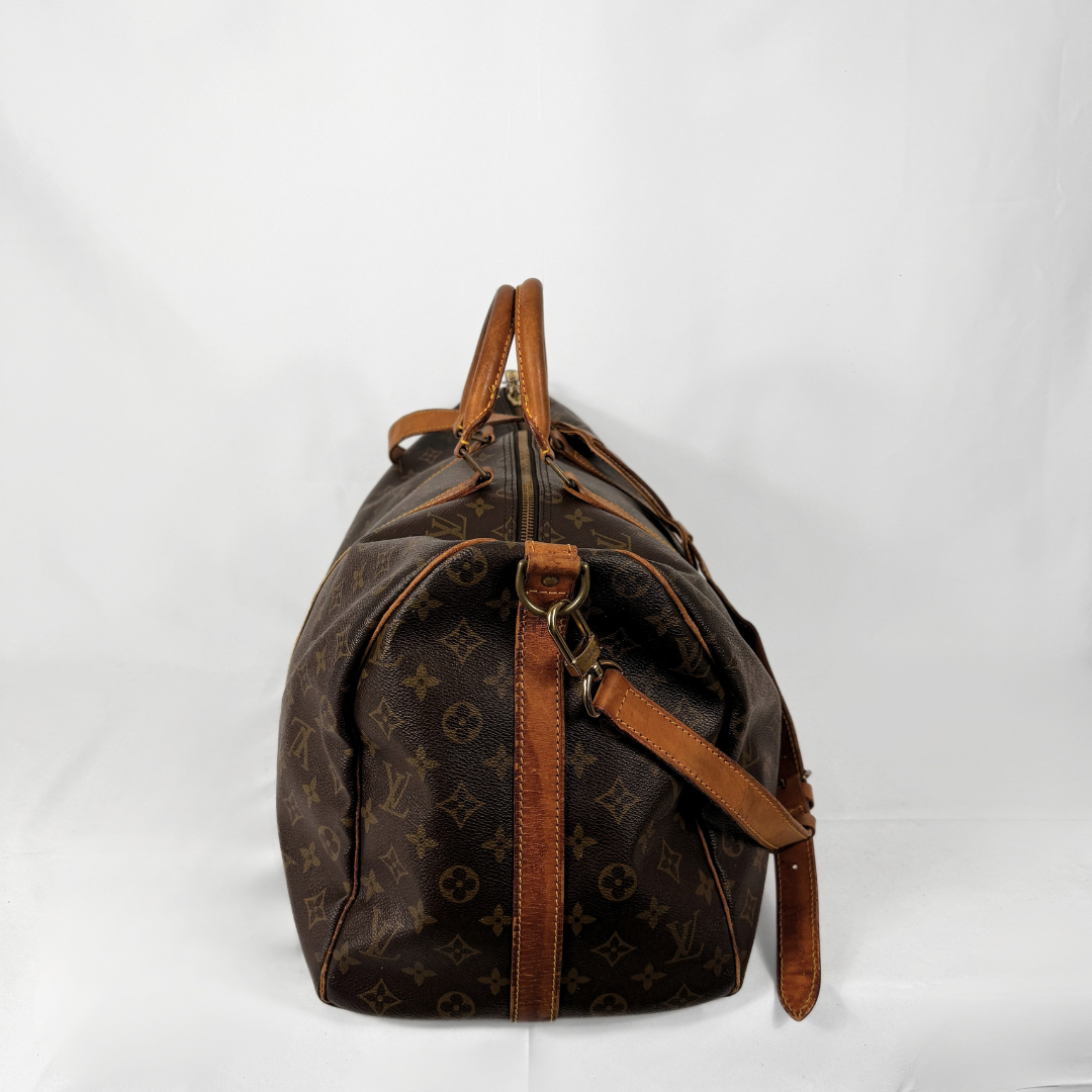 A Louis Vuitton monogram canvas duffel bag with brown leather trim and handles, photographed against a white studio background.