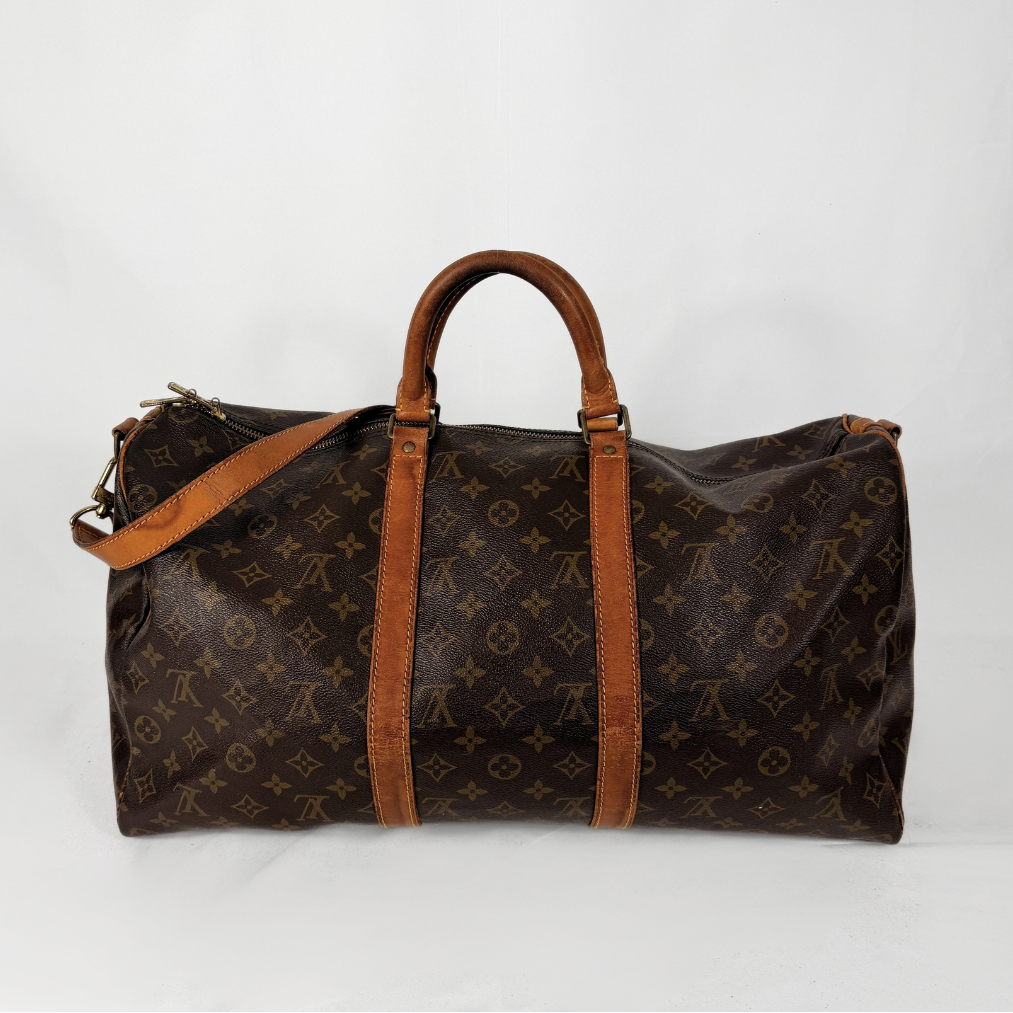 A Louis Vuitton monogram canvas duffel bag with brown leather handles and shoulder strap, photographed against a plain white background.