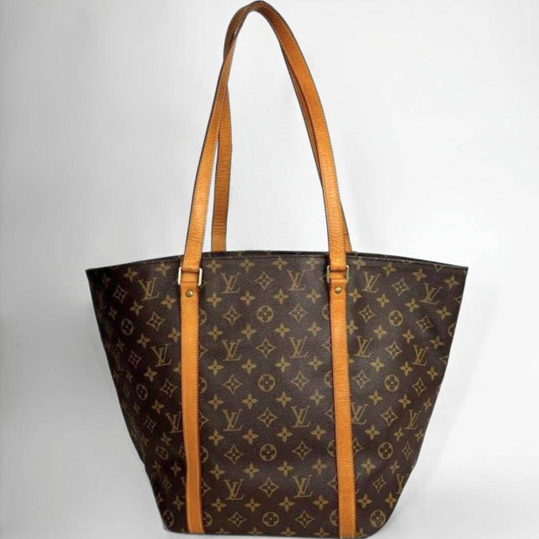 Louis Vuitton monogram canvas tote bag with tan leather shoulder straps and trim, shown against a plain light gray background.