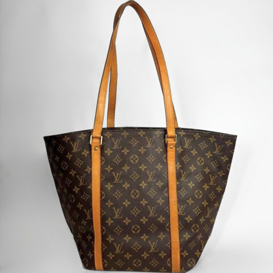 Louis Vuitton monogram canvas tote bag with tan leather shoulder straps and trim, shown against a plain light gray background.