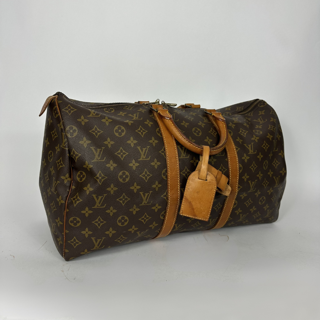Brown monogram patterned duffel bag with tan leather straps on a white background