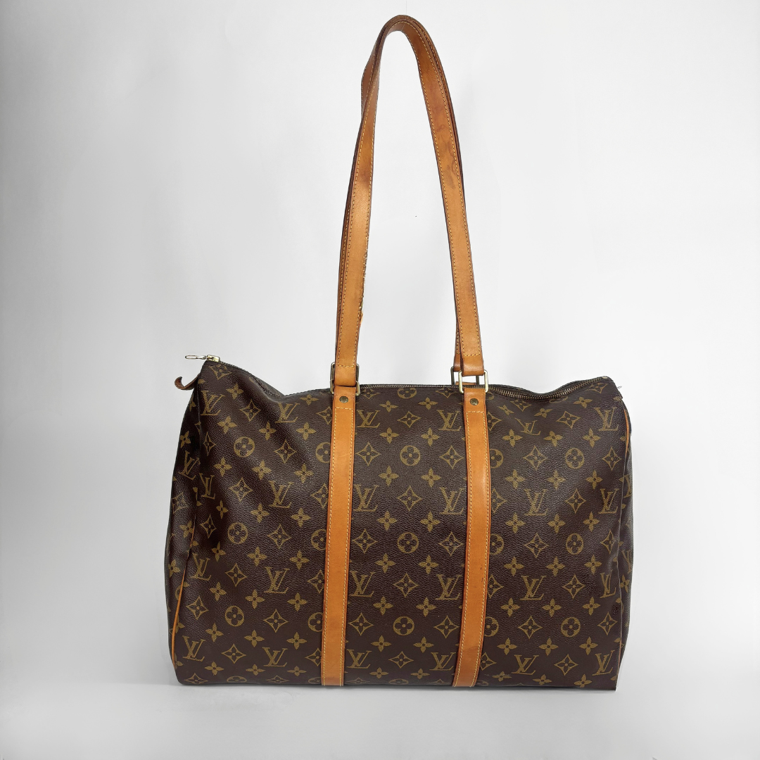 A vintage Louis Vuitton monogram canvas duffel bag with tan leather shoulder straps, photographed against a neutral light gray background.