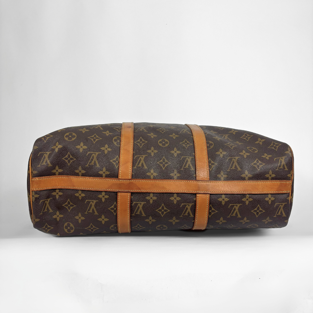 A Louis Vuitton monogram canvas duffel bag with tan leather straps, shown horizontally against a plain light gray background.