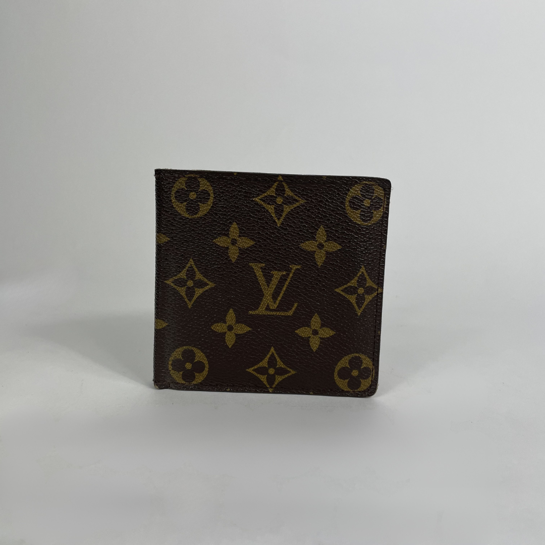 A Louis Vuitton monogram wallet in dark brown coated canvas with gold-tone printed motifs and an LV logo, standing upright on a light gray background.