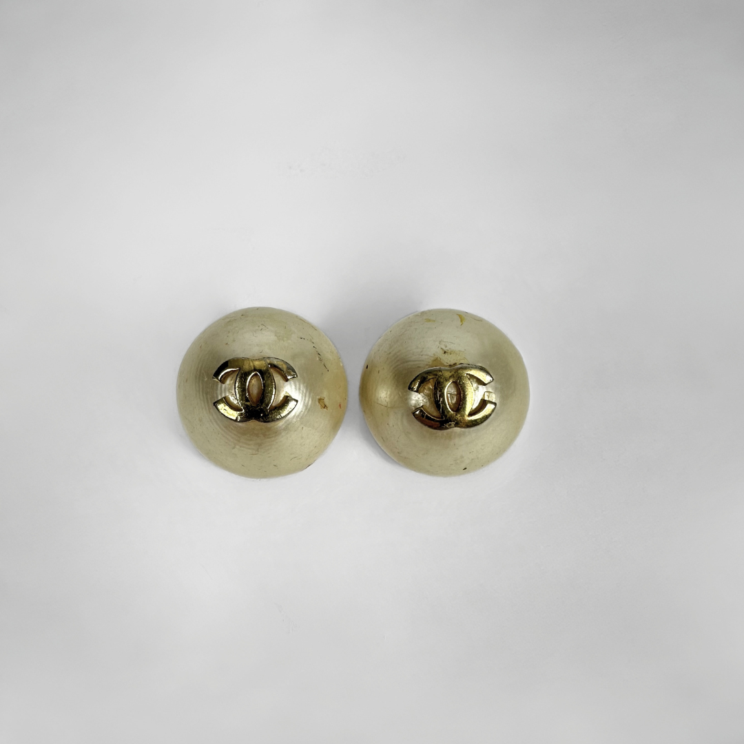 Two gold-tone round stud earrings shown from the back on a plain light gray background.