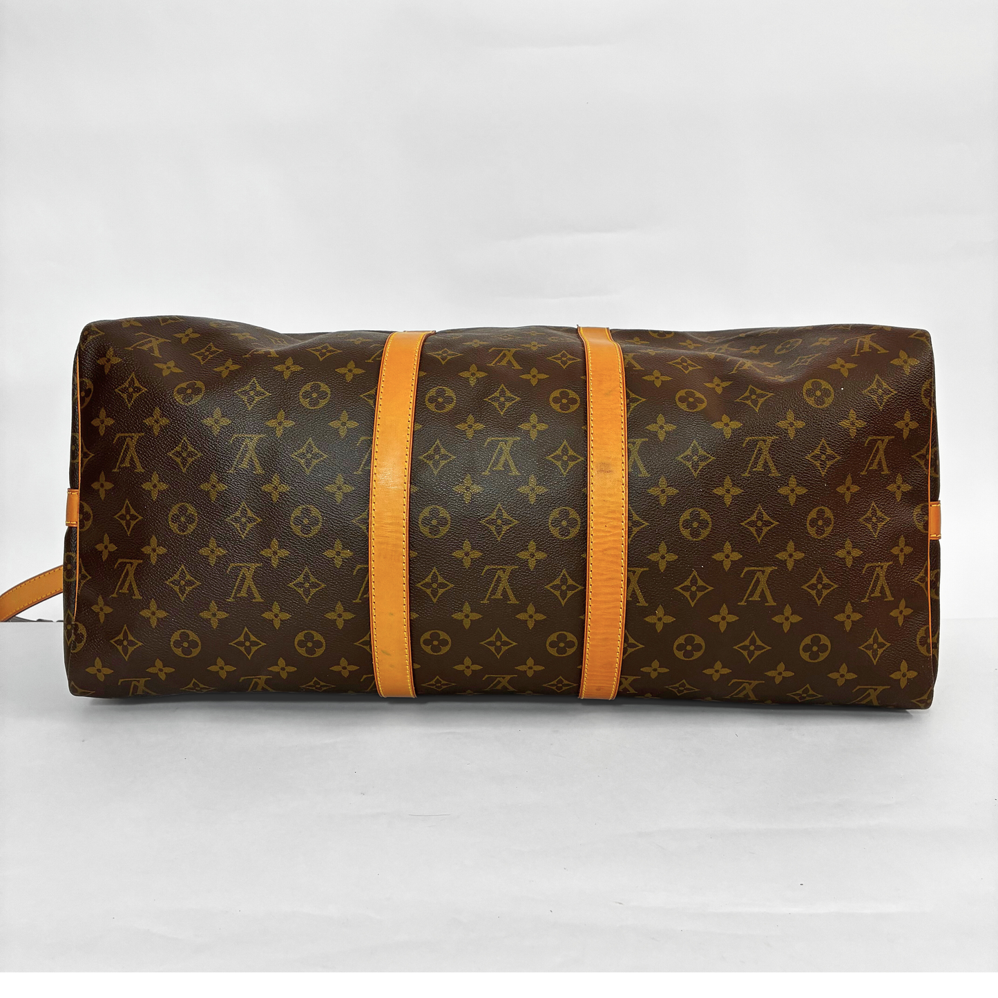 Brown leather bag with monogram pattern held open by black gloves on a white background