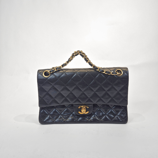 Black quilted handbag with gold chain handle and clasp on a white background