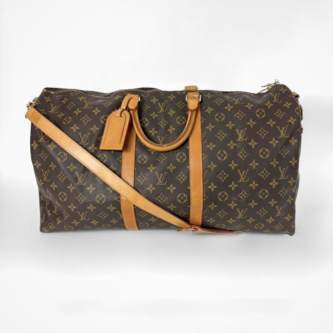 Brown monogram duffel bag with tan leather straps on a white background