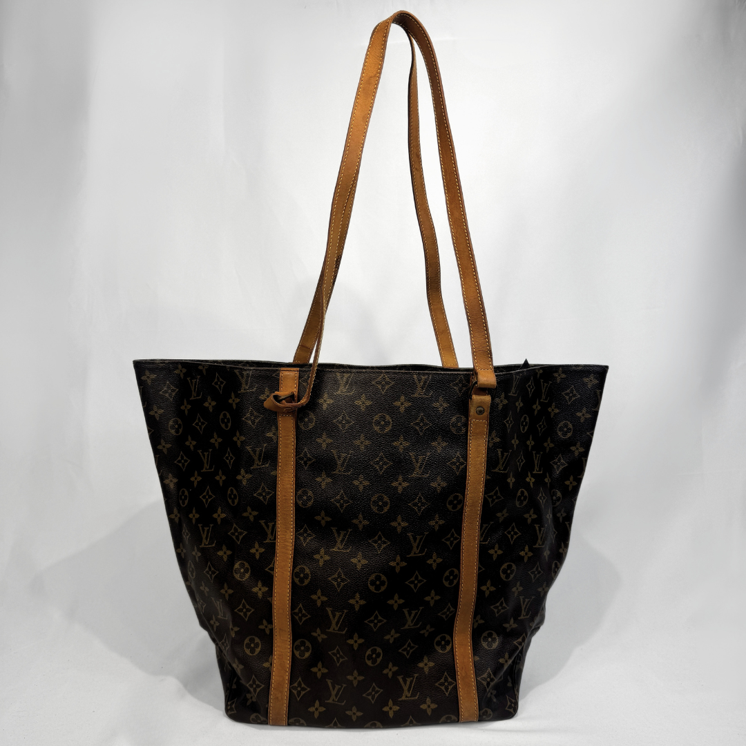 A Louis Vuitton monogram canvas tote bag with tan leather shoulder straps, photographed against a white studio background.