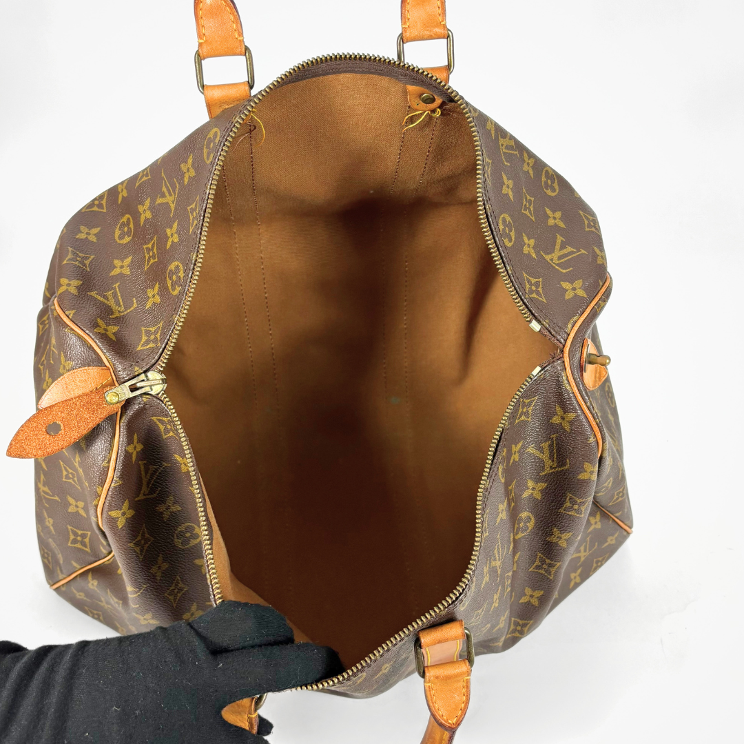 Louis Vuitton monogram backpack held by a gloved hand on a white background