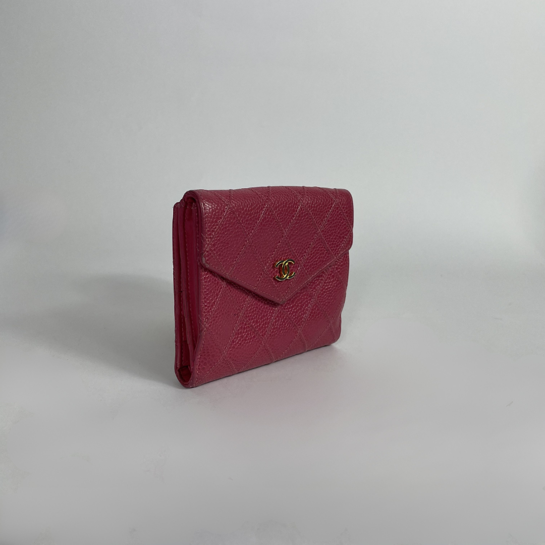 A small quilted leather wallet in a deep magenta pink, featuring a gold-tone interlocking CC logo on the front flap, set against a plain light gray background.