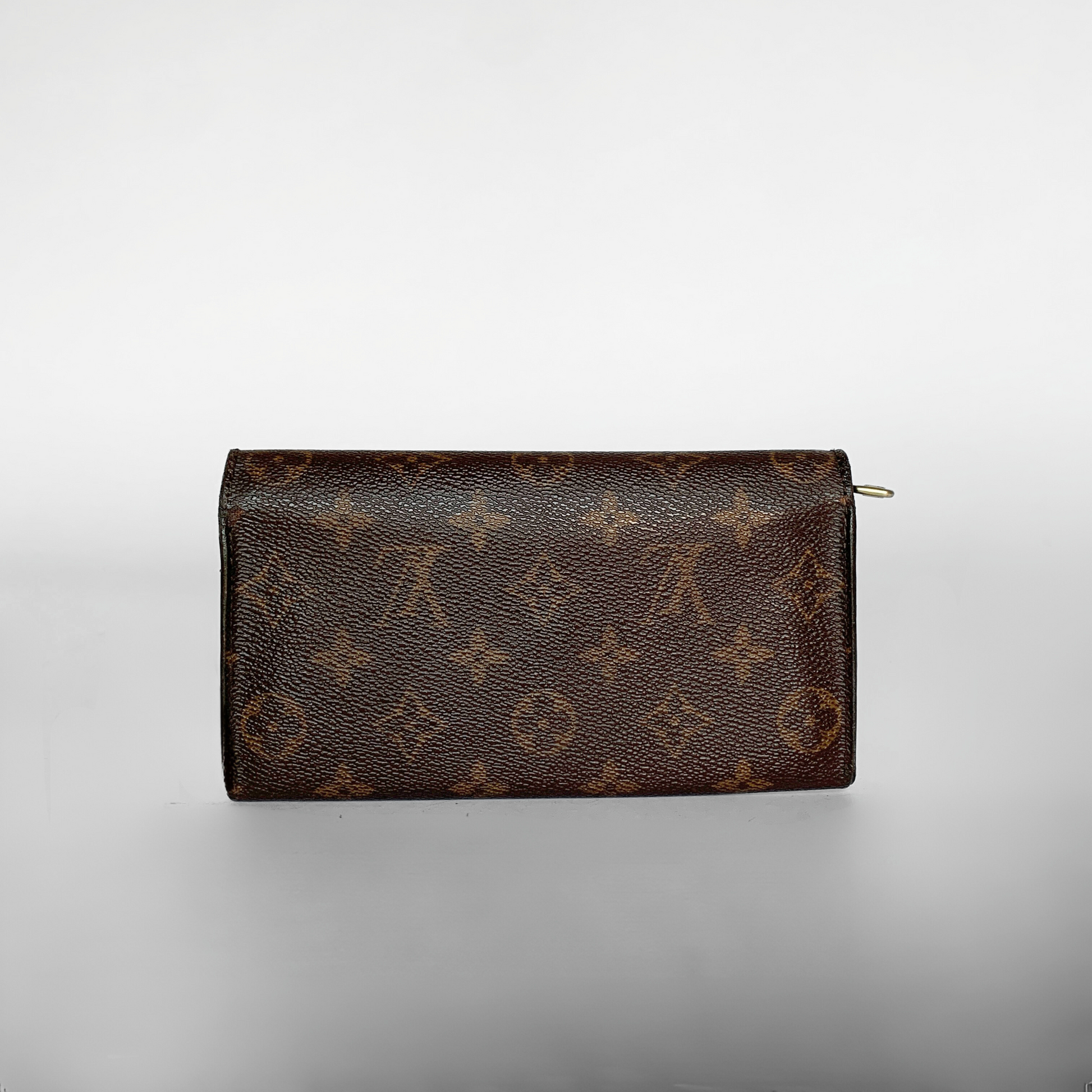 A Louis Vuitton monogram canvas zip-around wallet in dark brown with tan monogram motifs, photographed on a light gray gradient background.