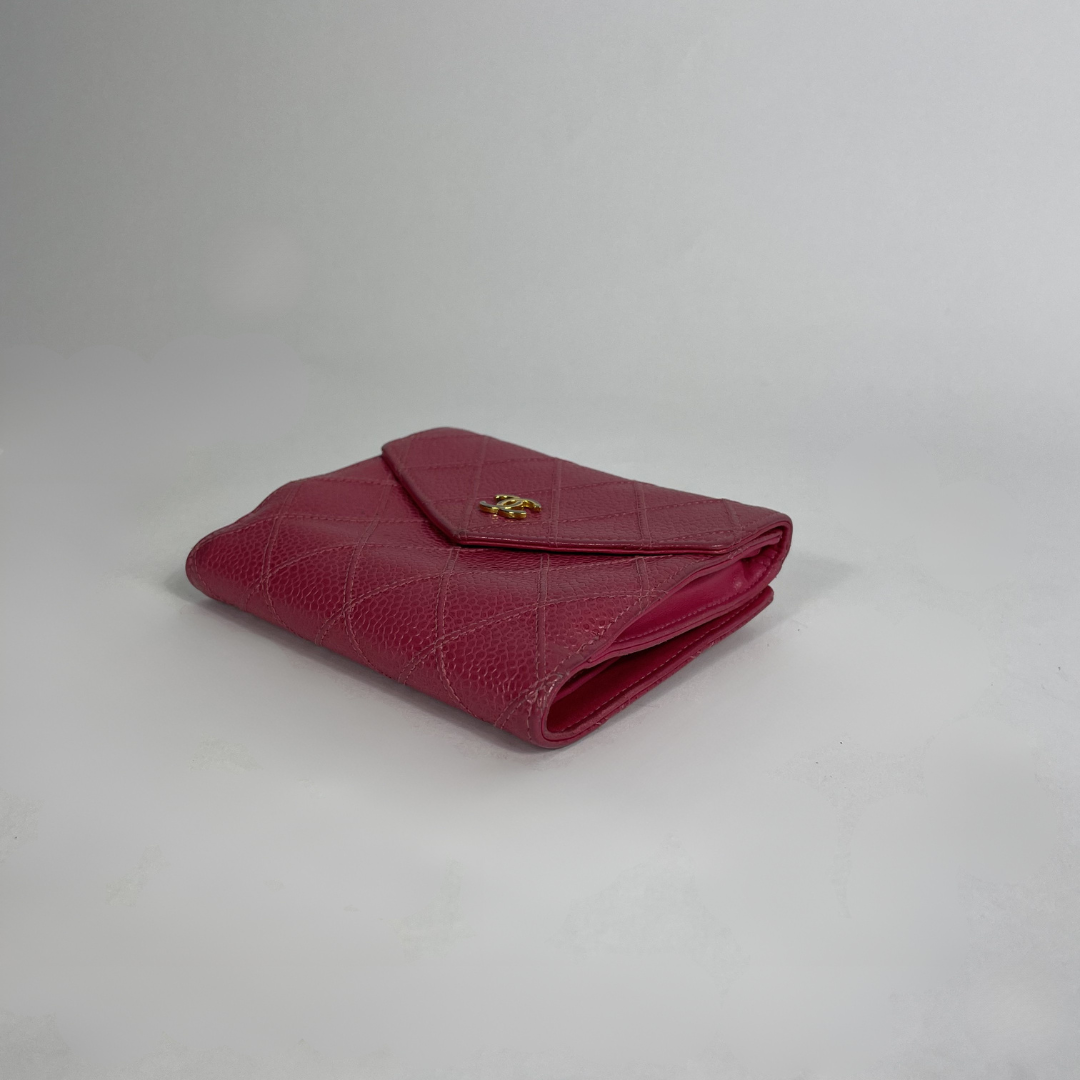 A folded red quilted leather wallet with a small gold-tone logo clasp, photographed on a light gray studio background.