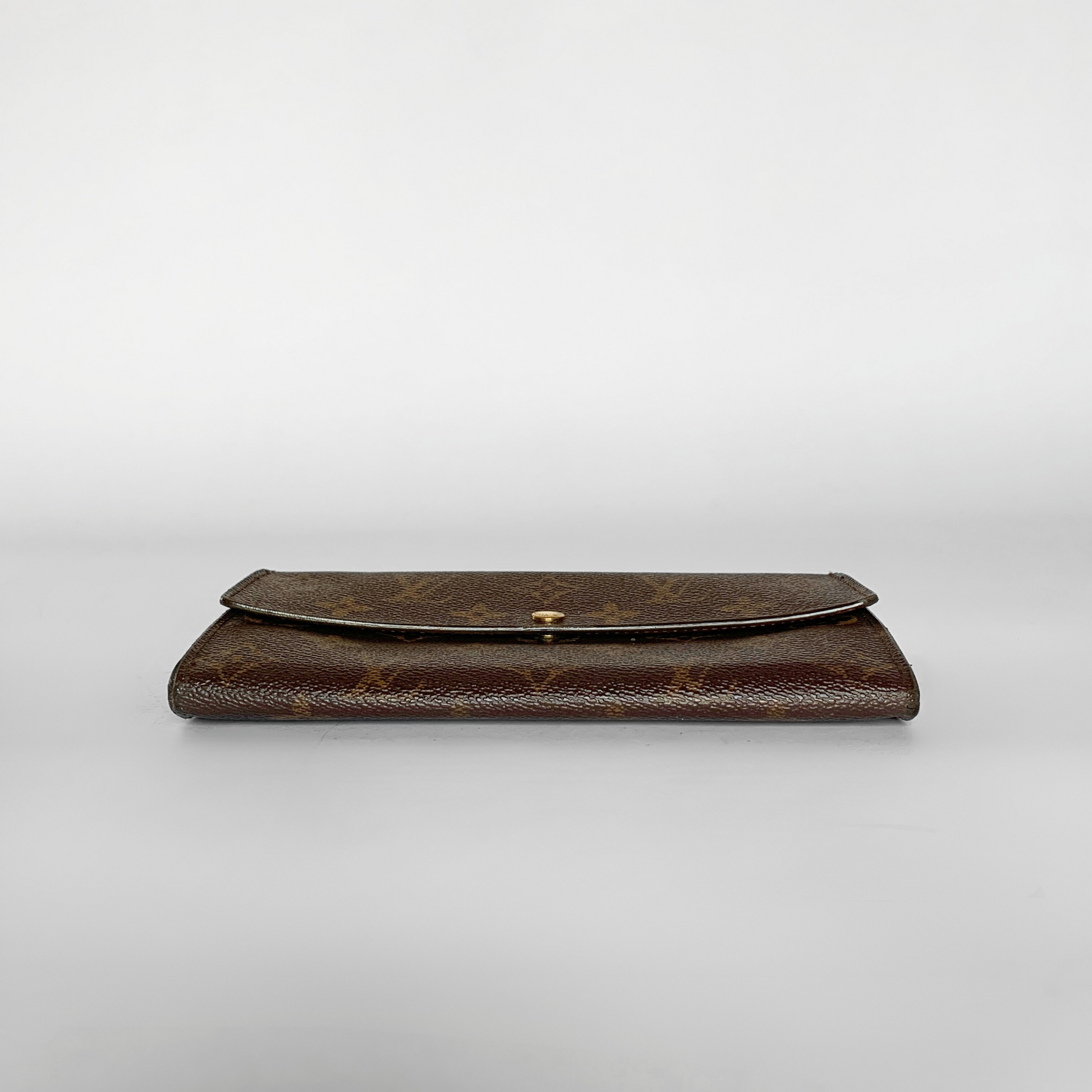 A brown monogram wallet with a flap closure and a small gold clasp, photographed against a neutral light gray background.