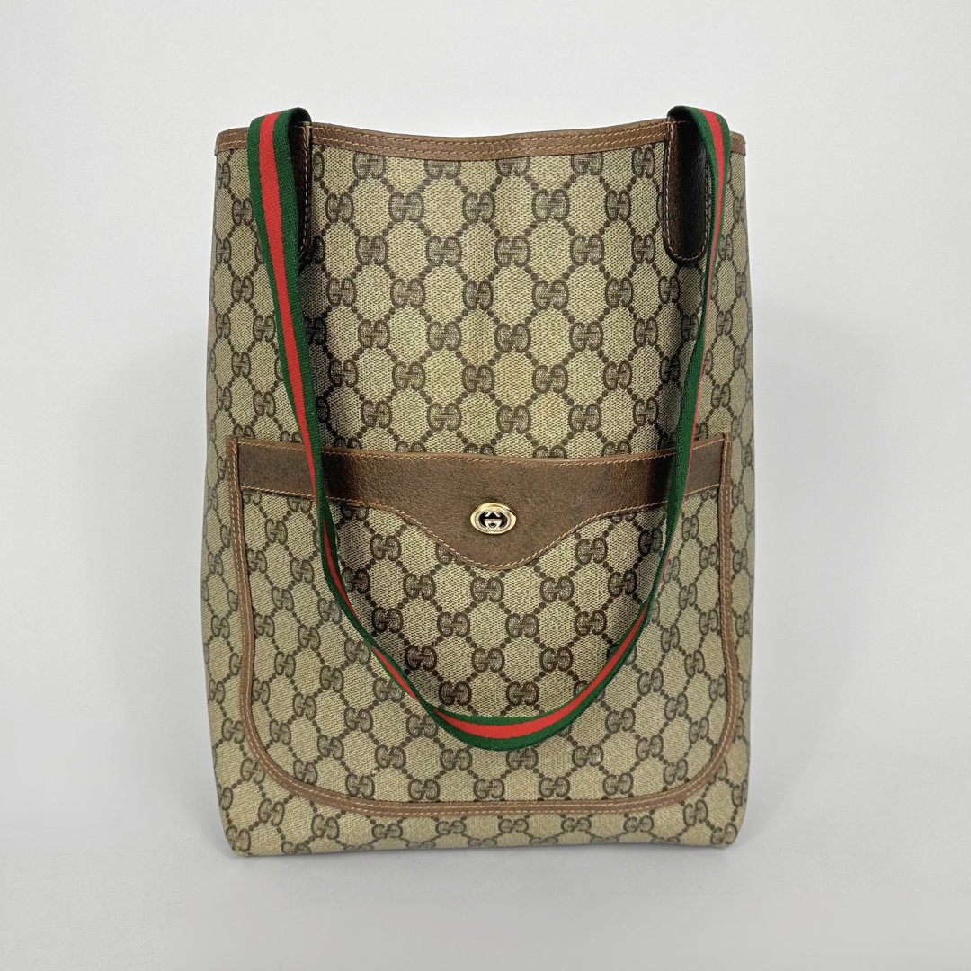 Designer handbag with patterned fabric and brown accents on a light gray background