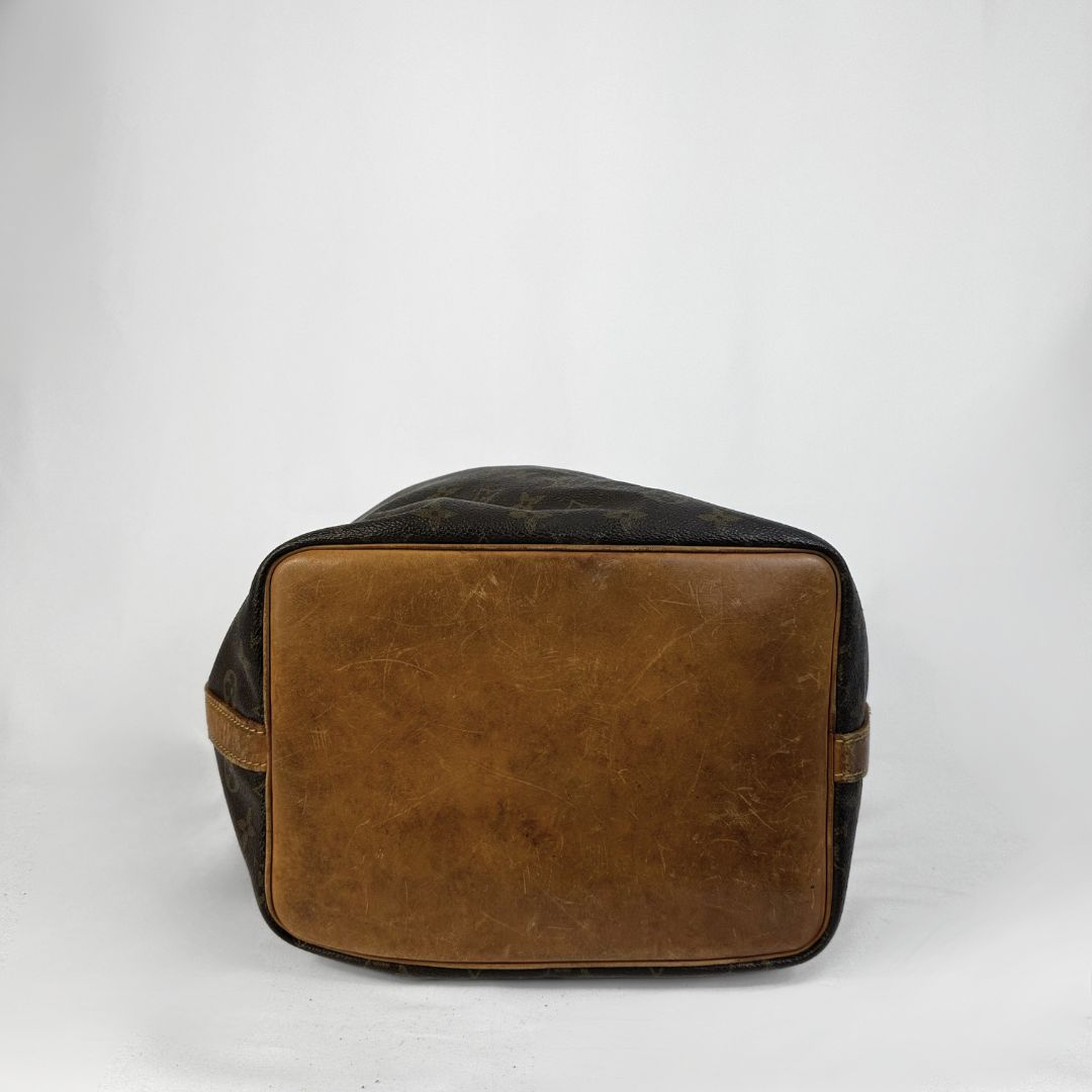 A vintage Louis Vuitton duffle bag in brown and black monogram canvas, photographed from the back against a light gray studio background.