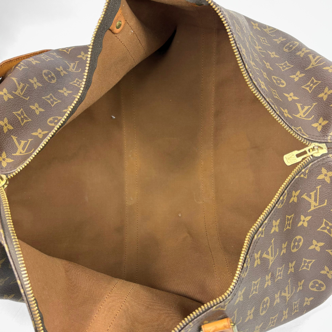Brown duffel bag with tan leather straps and handle on a white background