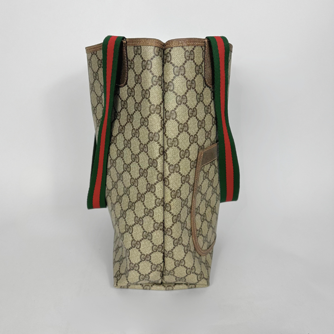 Designer tote bag with monogram pattern and red and green stripes on a light gray background