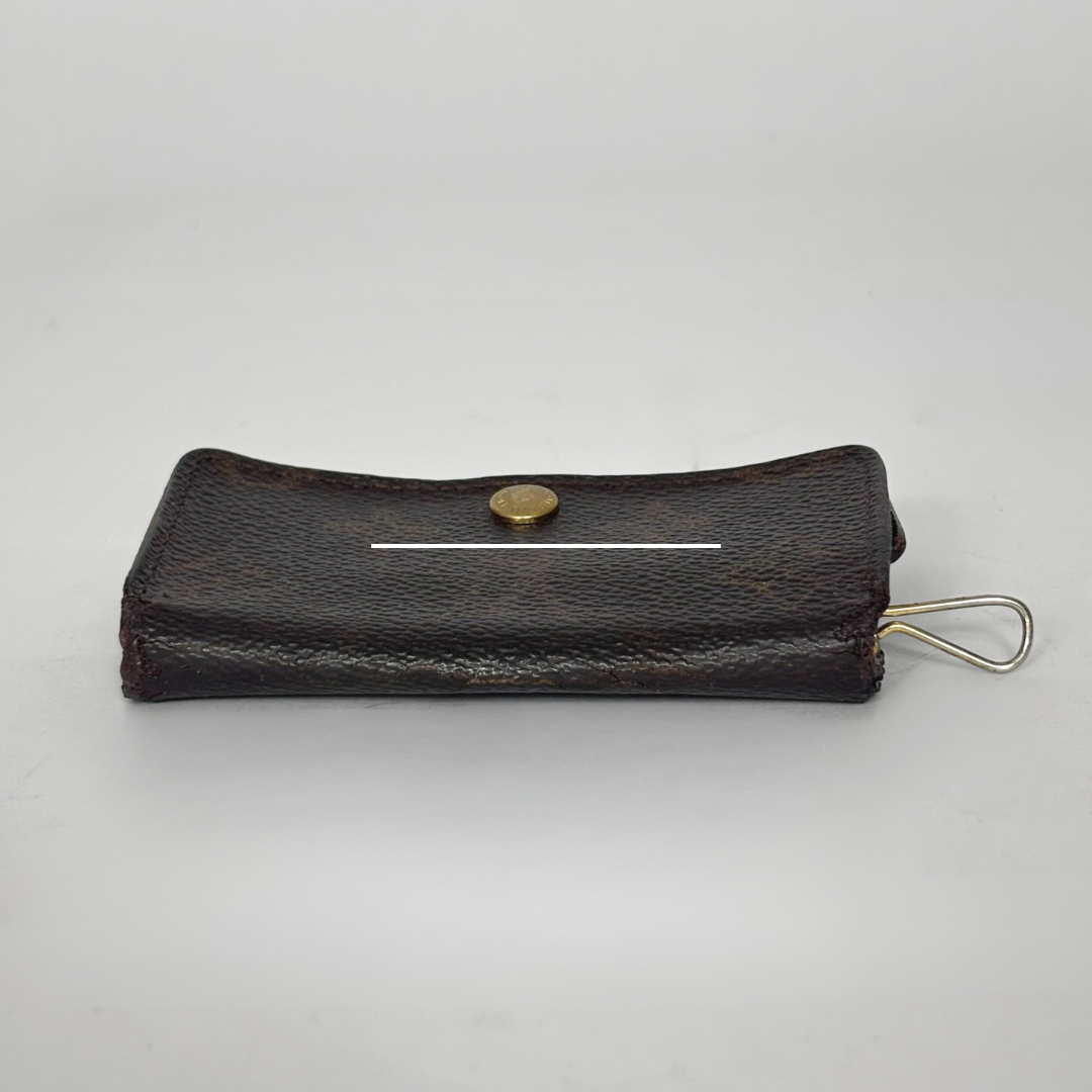 Black leather key case with a gold button and keychain on a light gray background