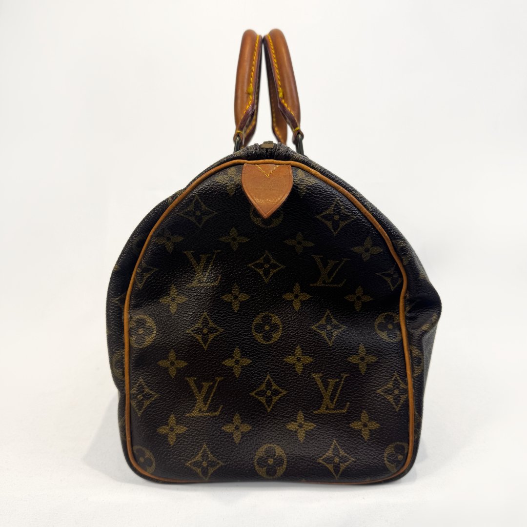 A Louis Vuitton monogram canvas Speedy handbag with brown leather handles and trim, photographed against a plain white background.