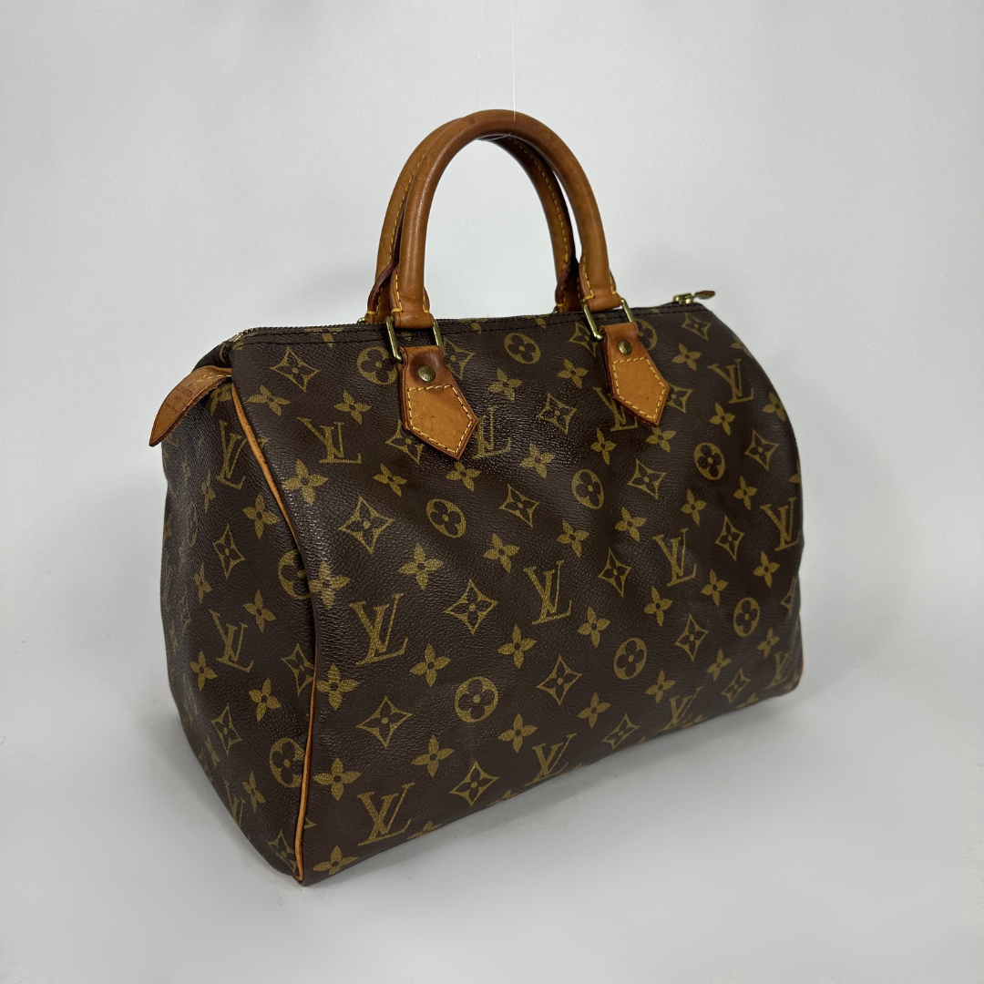 A Louis Vuitton monogram canvas duffle bag with brown leather handles and trim, photographed on a light gray studio background.