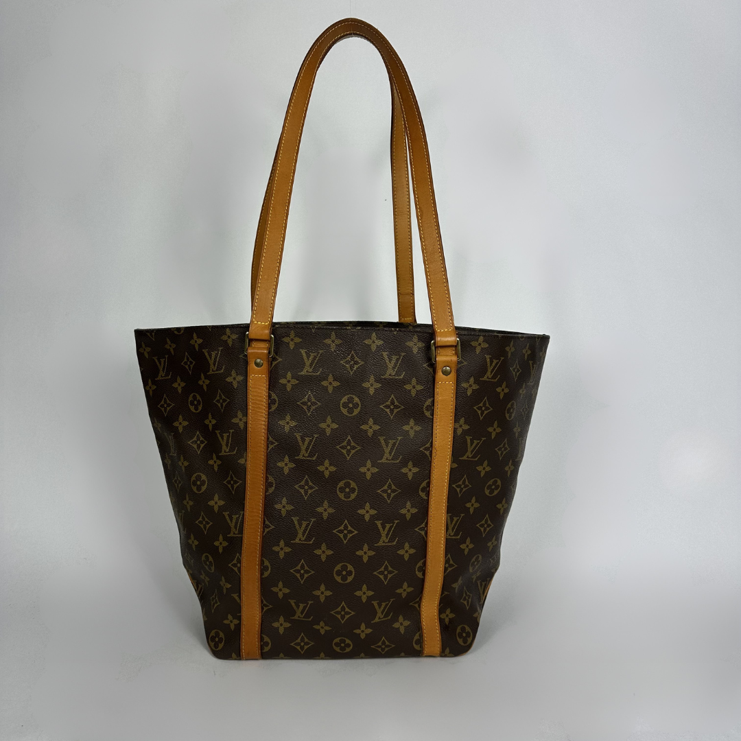 Louis Vuitton monogram canvas tote bag with tan leather shoulder straps, shown against a plain light gray background.