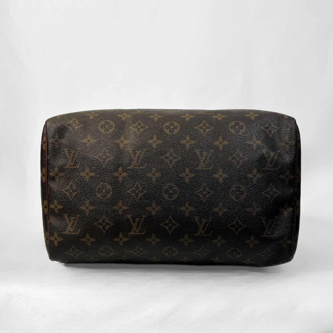 A Louis Vuitton monogram canvas shoulder bag in dark brown with tan monogram motifs, photographed against a light gray fabric background.