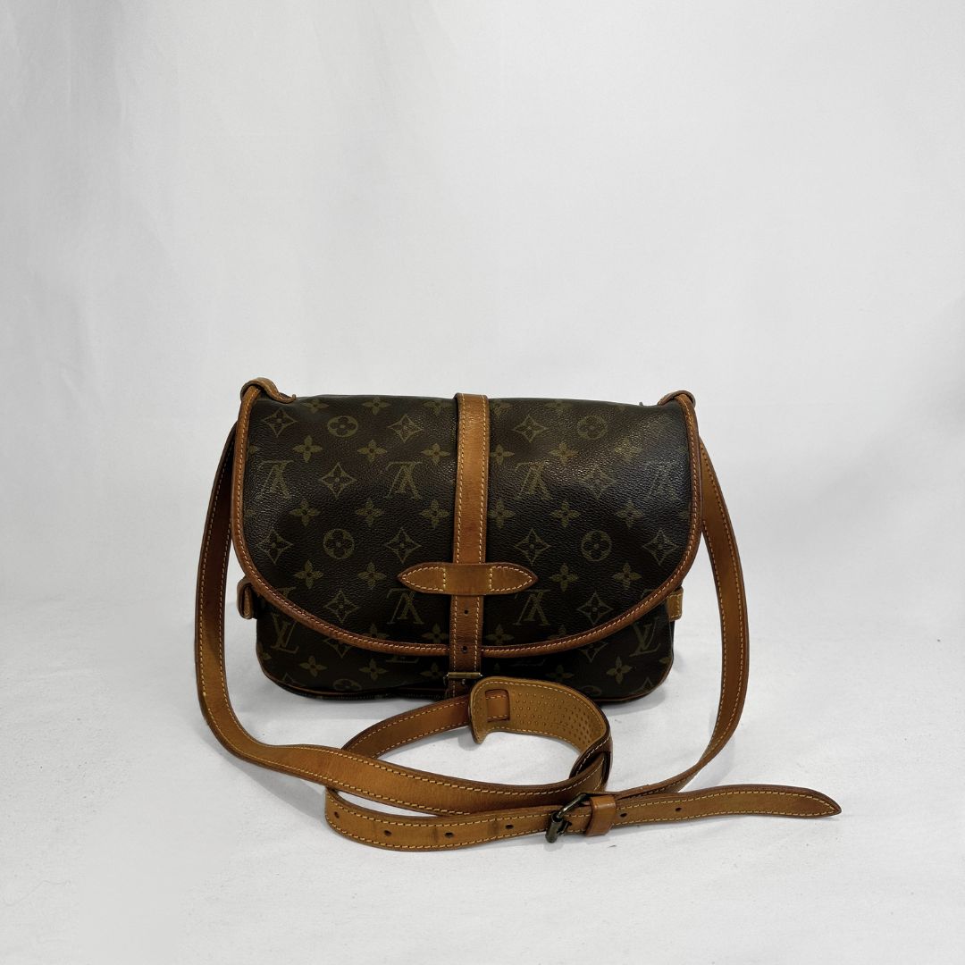 Louis Vuitton monogram canvas shoulder bag with tan leather trim and strap, photographed against a plain light background.