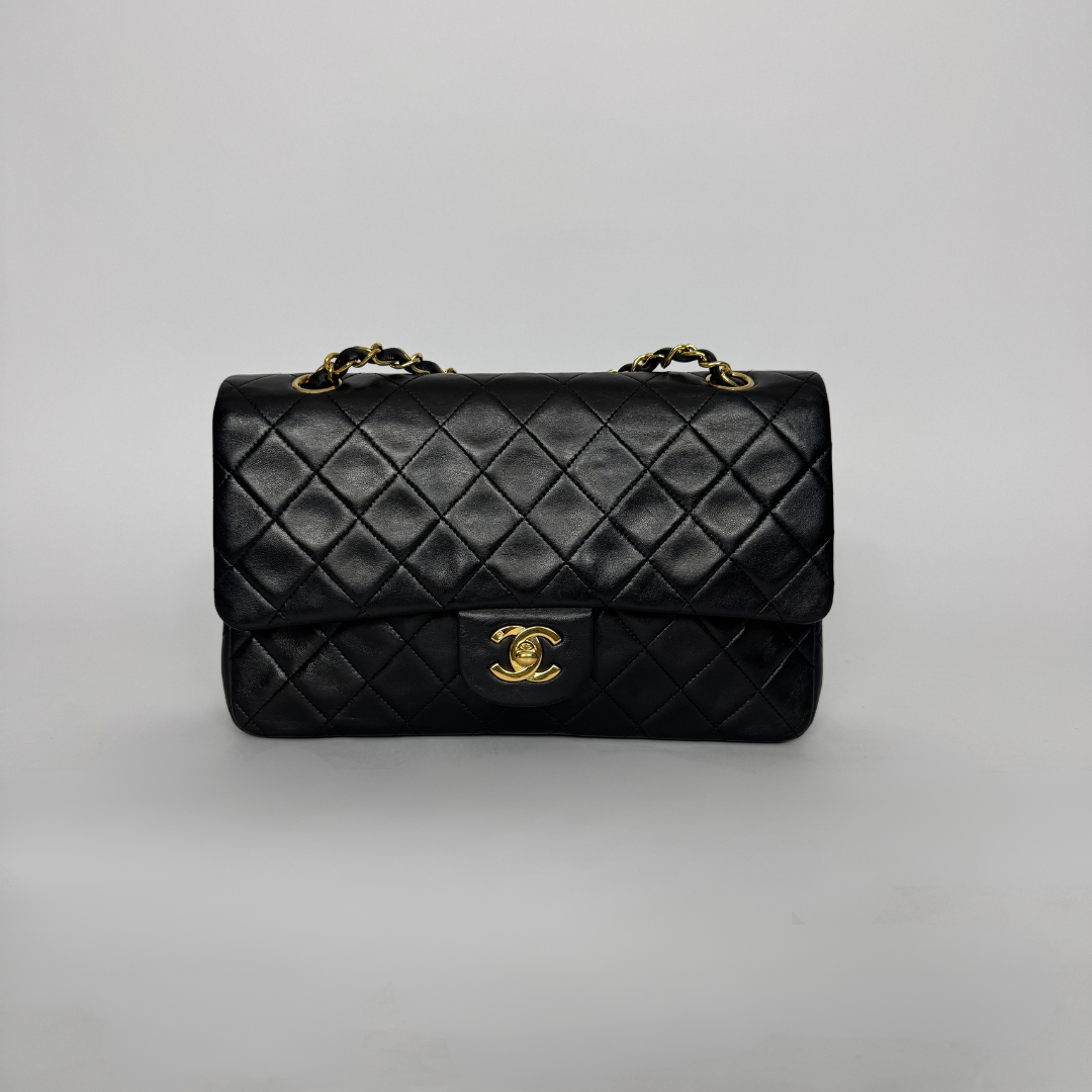 Black quilted handbag with gold hardware on a light gray background