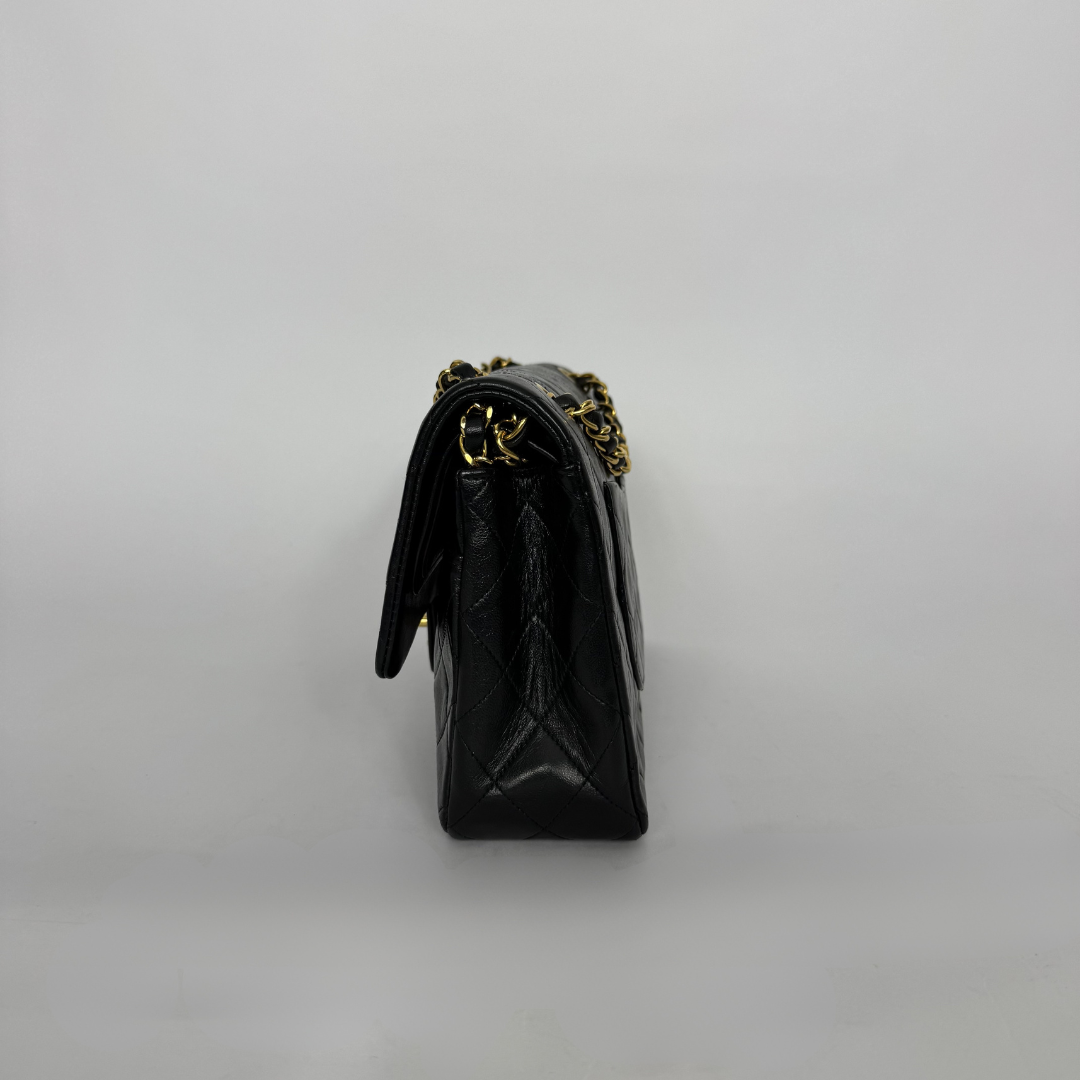Black handbag with gold chain strap on a light gray background