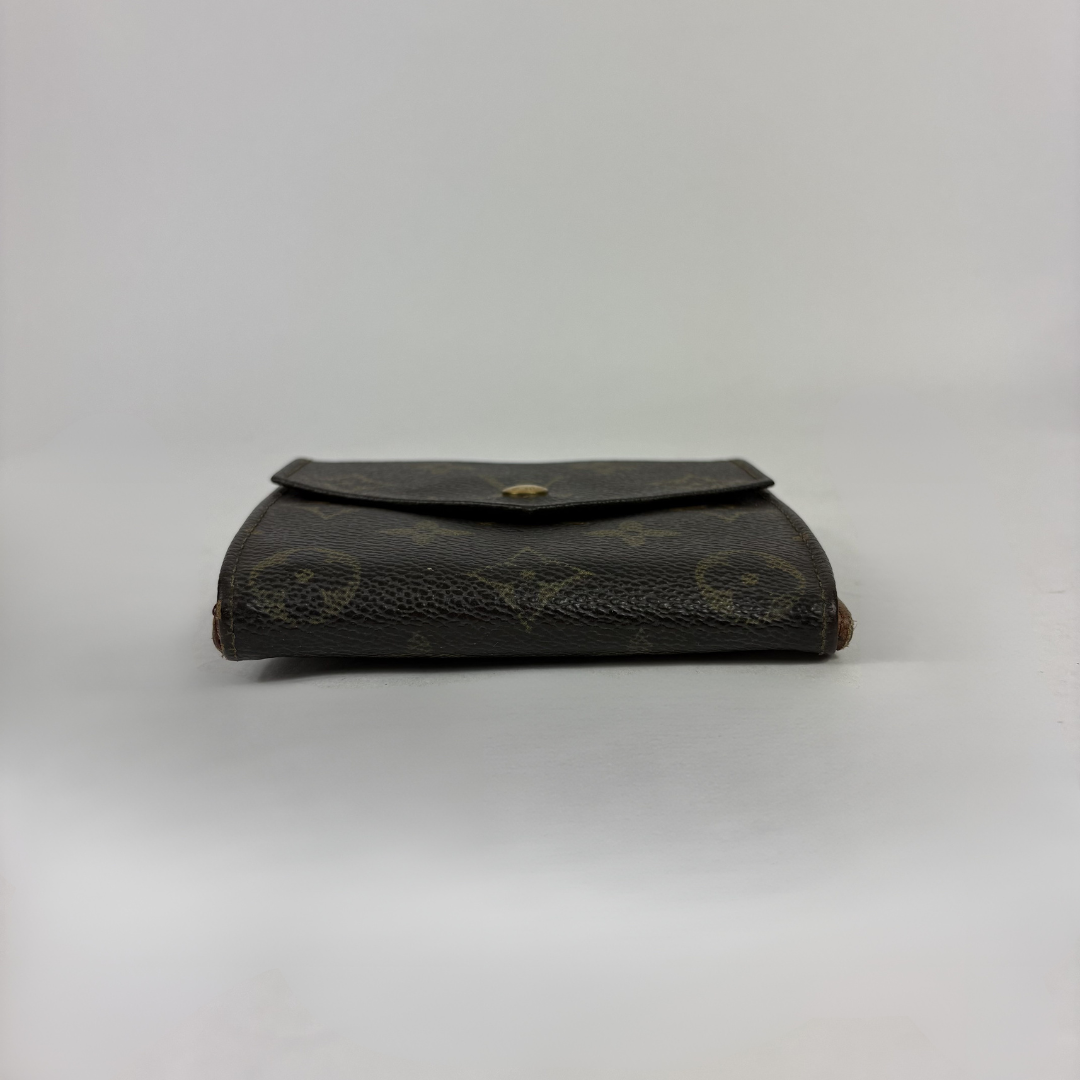 A Louis Vuitton monogram canvas wallet in dark brown with gold-tone hardware, photographed against a neutral light gray background.