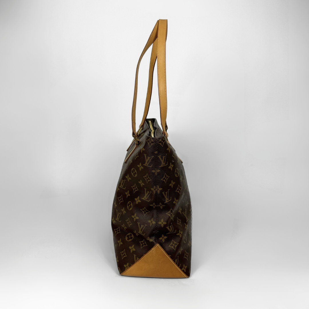 Brown monogram handbag with tan leather handle on a white background