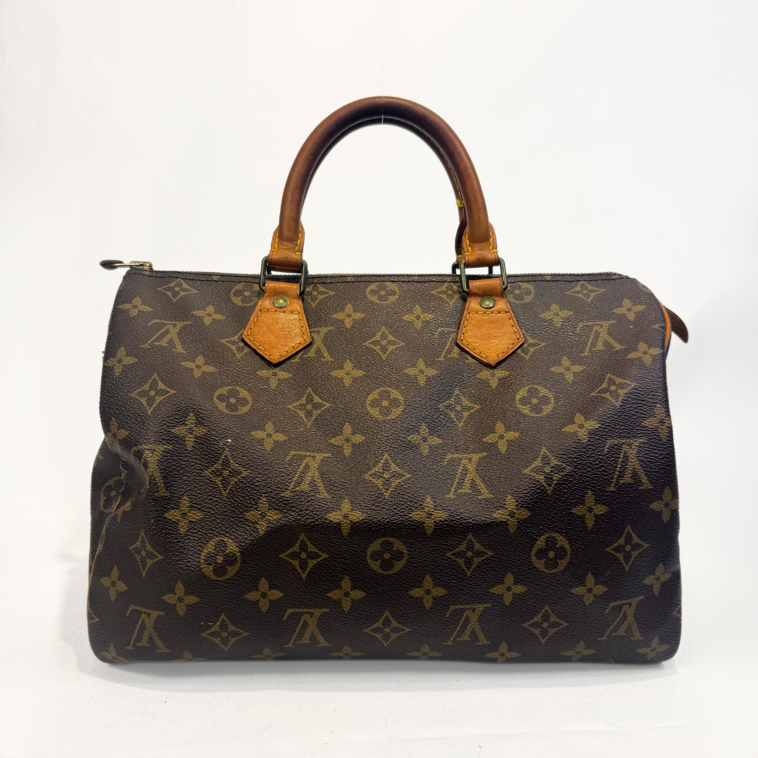 A Louis Vuitton monogram canvas Speedy handbag with brown leather handles and gold-tone hardware, photographed against a plain white background.